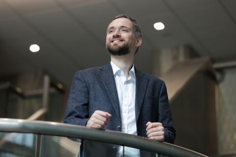 Joseph Greene poses looking upward while standing in a stairway.