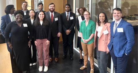 Group of Georgia Tech researchers and students standing indoors at a professional event, wearing business attire and conference name badges.