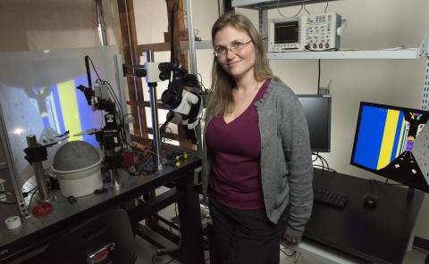 Annabelle Singer, lead researcher on the project, standing in her lab smiling next to equipment.