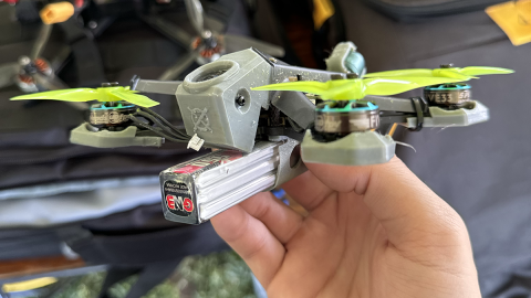 Multi-rotor drone racing device, held in hand by a pilot.