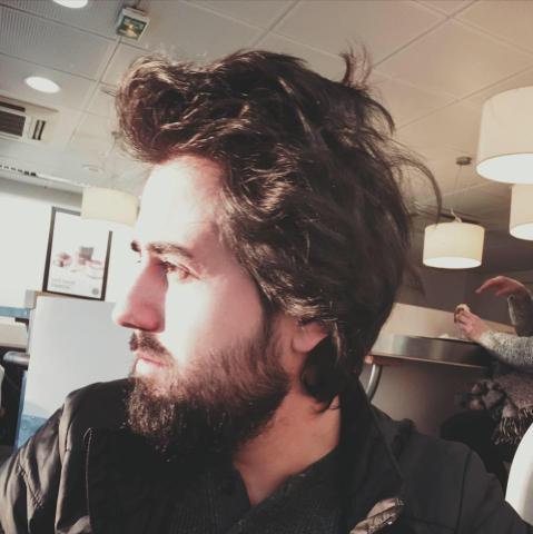 A side profile of a man's face. He has long hair and a beard