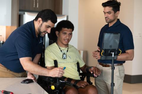 two researchers and a patient in a wheelchair using assistive technology