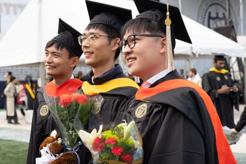 Group of three Georgia Tech students at commencement ceremony with flowers.