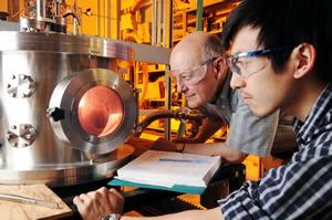 Professor Dennis Hess and graduate research assistant Lester Li observe oxygen plasma treatment that exposes the cellulose nanofibrils on their superamphiphobic paper samples. (Georgia Tech Photo: Gary Meek)