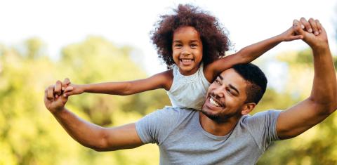 Father carrying daughter on back outdoors