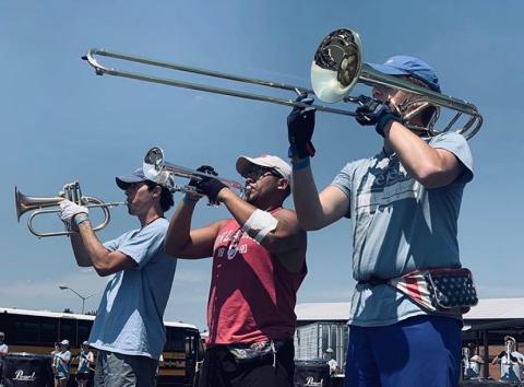 Three Spirit of Atlanta members hold brass instruments to play as a trio.