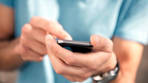 Person in a blue shirt holding a cell phone