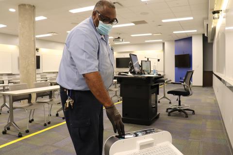 Albert Williams (A/C Mechanic II) installs an air scrubber in a classroom.