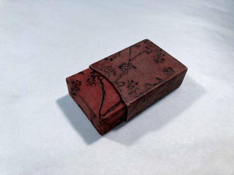 A reddish-brown 2-part box. One section is partially slid out, revealing an embossed design on the box. 