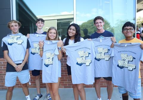 Photo of group of students holding Week of Welcome t-shirts.