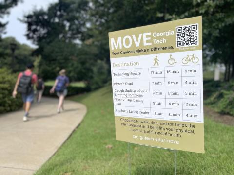 Image of Move Georgia Tech yard sign next to path with students walking.