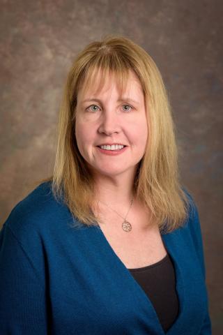 Headshot of a woman with blonde hair and a blue jacket.