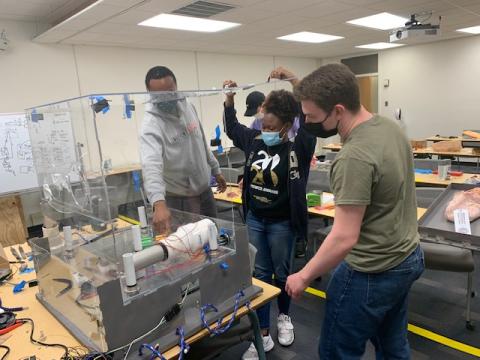 Teammates Ismael Dondasse, Breanna Ivey, and Ben Leverett discuss the electronics housing and how to run the wires through the enclosure.