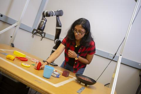 Lakshmi Nair assembles tools on a table next to a robotic arm