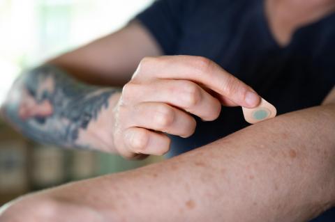 A person presses a tattoo patch to their arm