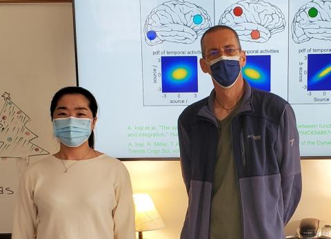 Two researchers standing by a board showing brain imagery 