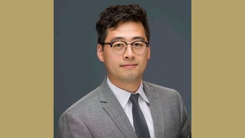 Headshot of Daniel Aum on a gold background.