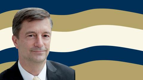 A headshot of Michael Polak on top of alternating navy, gold, and white curved stripes.