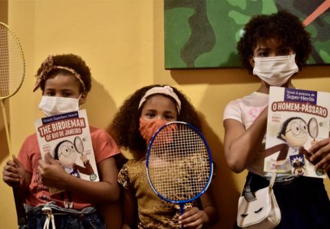 Children in Rio de Janeiro's favelas stand with their badminton equipment and copies of The Birdieman of Rio de Janeiro, written by George P. Burdell.