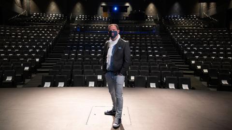Aaron Shackelford, director of Georgia Tech Arts, wearing a mask, standing alone on stage Aaron Shackelford, director of Georgia Tech Arts, wearing a mask, standing alone on stage with the theater seats of the Ferst Center for the Arts visible behind him. Partially visible are the white pieces paper pinned to more than 700 of the seats to mark physically distanced seating.