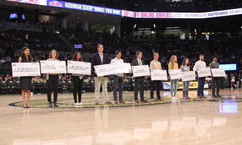 Students stand in McCamish Pavilion with large checks from the Georgia Tech Student Foundation.
