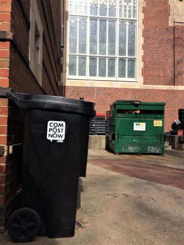 Black composting bin located near the dumpsters behind Brittain Dining Hall.