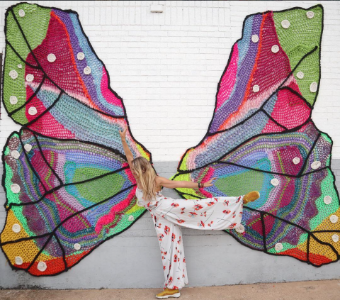 woman posing in front of a large crochet butterfly