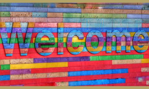 multicolored wooden letters, on a multicolored wood background, spelling out the word WELCOME