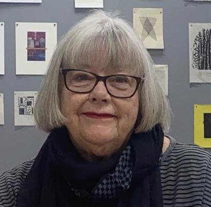 Image of woman facing the camera, wearing glasses. Her hair is chin length, and she is wearing a dark shirt with a navy blue scarf around her neck