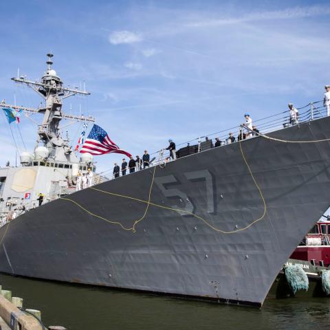 Crewmen stand on the deck of a U.S. Navy destroyer ship.