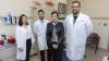 School of Interactive Computing Associate Professor Rosa Arriaga, in a black leather jacker, poses for photo with three researcher collaborators each wearing white lab coats.