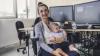 A woman with a baby on her lap poses for a photo in an office.