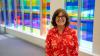 a photo of Victoria Thompson in front of a panel of colored windows