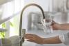 A person fills a glass of water from a faucet 