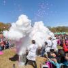 A crowd gathered around people in lab coats standing next to large, smoking vessels during a science experiment in Piedmont Park