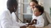 A pediatrician listens to a young patient's heartbeat with a stethoscope.