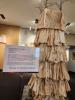 a tower made from layers of heavy paper, with branches reaching toward the sky from each corner