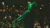 Image of a performer from behind, singing on stage in front of a crowd.