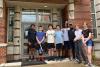 Eight students standing in front of a brick residence hall