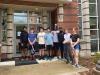 Eight students standing in front of a brick residence hall.