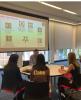 Three students sit at a round table across from a man.