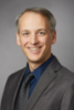 Jeffrey Townsend smiling with grey and navy-blue suit.