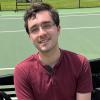 Headshot of a man standing on a tennis court