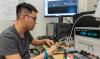 Tzu-Han Wang working on a circuit board with an analog chip connected to pattern generator instruments used to create continuous waveforms to test and analyze the performance of the chip.    