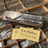Metal type in a wooden container with a composition stick and yellow calling card