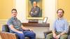 David Muchlinski and Chandler Thornhill sit facing the camera in front of a yellow wall with a portrait of former Sen. Sam Nunn.