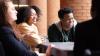 Three students sit at a table laughing.