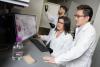 Lena Gamboa and Gabe Kwong look at colorized cells on a computer monitor while Ali Zamat loads samples into a cell counting device. (Photo: Candler Hobbs)