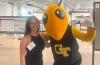 A young woman stands with the Georgia Tech mascot Buzz