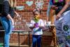 child holding a flower while surrounded by adult helpers